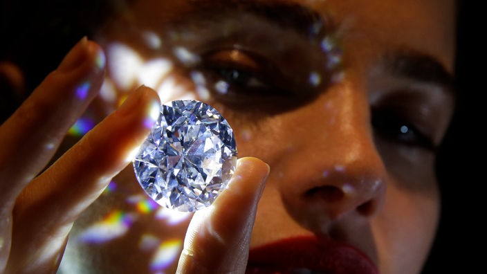 Eine Frau hält einen funkelnden Diamanten in der Hand
