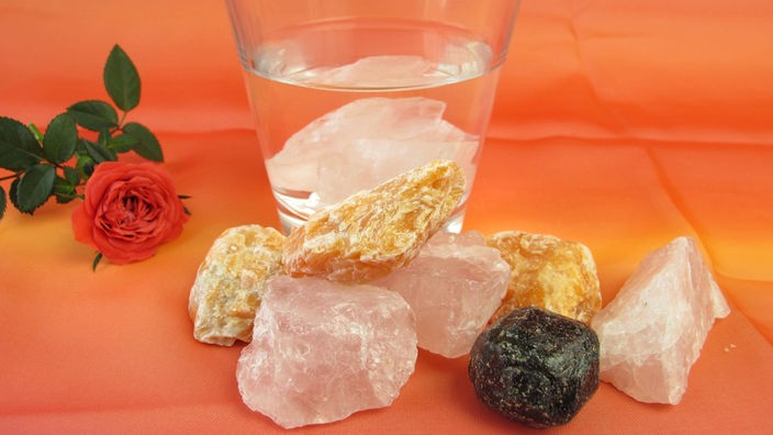 Große Mineralsteine vor einem Glas Wasser
