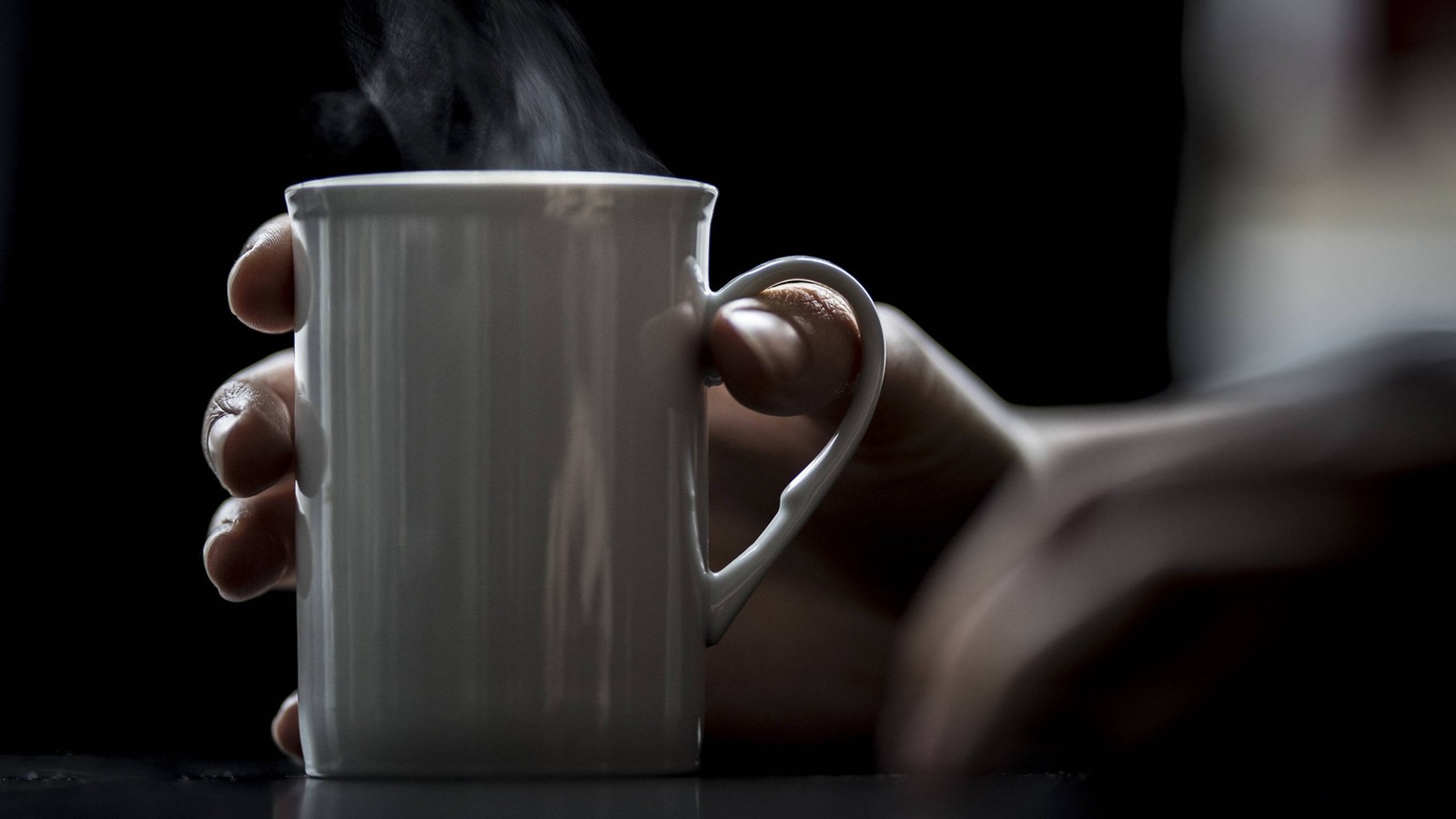 Eine Hand hät eine dampfende Tasse.