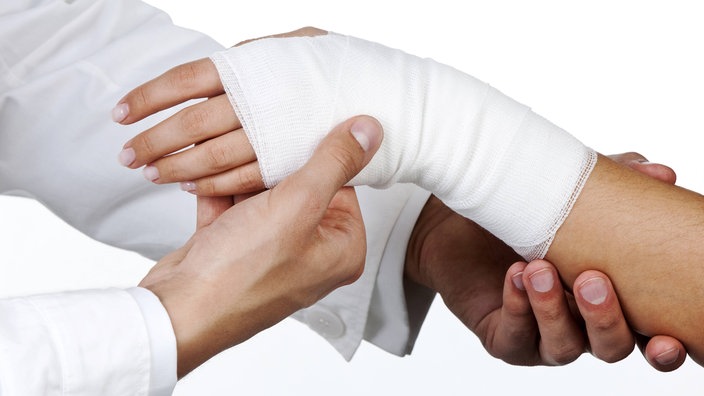 Ein Arzt verbindet eine Hand. | Bildquelle: imago Ein Arzt verbindet eine Hand.