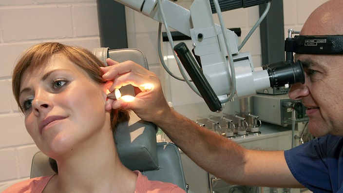Ein Hals-Nasen-Ohren-Arzt untersucht das Ohr einer Patientin.