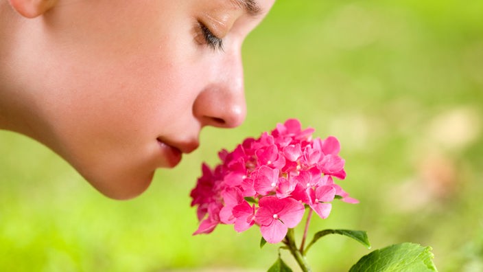 Eine Frau riecht an einer Blüte