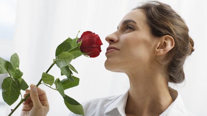 Frau riecht an Rose.