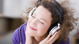 Eine Frau hört über Kopfhörer Musik.