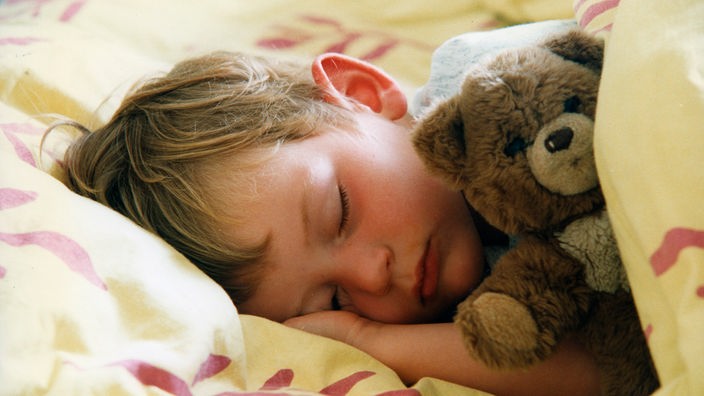 Kind mit Teddybär im Bett