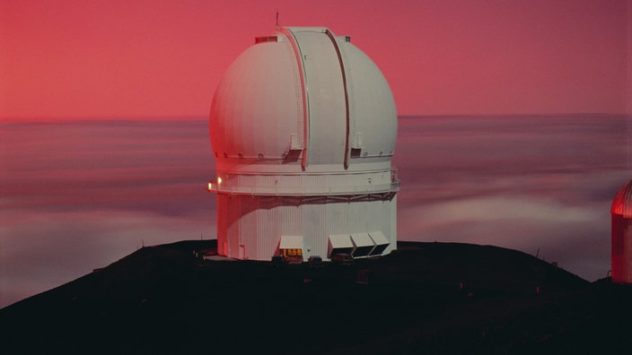 Luftaufnahme einer vulkanischen Bergspitze, auf der sich ein Observatorium befindet. | Bildquelle: Mauritius Images Luftaufnahme einer vulkanischen Bergspitze, auf der sich ein Observatorium befindet.