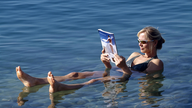 Eine Frau liest ein Buch beim Schwimmen im Toten Meer
