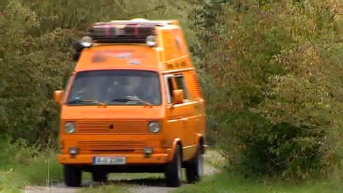 Das Bild zeigt einen orangen VW T3 Bus.