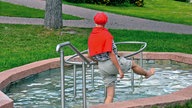 Frau beim Waden-Kneippen in einem Wasserbecken