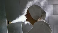 Eine Frau atmet Dampf aus einem Inhalator
