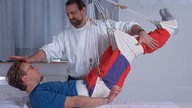 Therapeut und Patient bei Ergotherapie am Schlingentisch