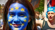 Frontalaufnahme einer jungen Frau, deren Gesicht als die europäische Flagge angemalt ist.