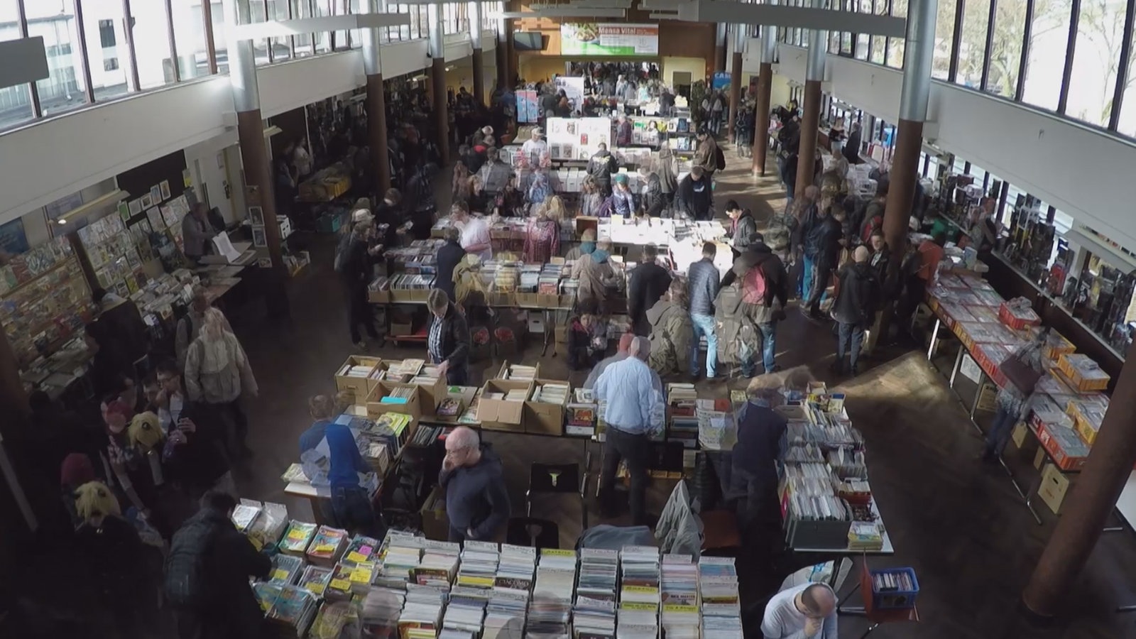 Blick von oben auf eine Comic-Messe: viele Menschen betrachten Comics und handeln damit.