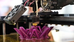 Ein 3-D-Drucker druckt eine lila Figur