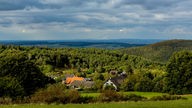 Landschaft mit Wiesen, Wäldern und bewölktem Himmel in der Eifel