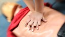 Zwei Hände üben an einer Puppe die Herzdruck-Massage