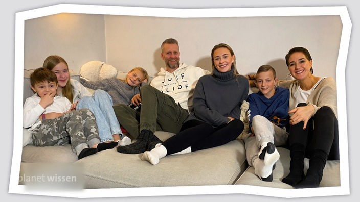 Eine Familie auf dem Sofa: Vater, Mutter und fünf Kinder