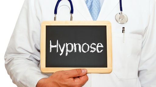 Ein Mann in einem Arztkittel hält eine Tafel, auf der „Hypnose“ steht