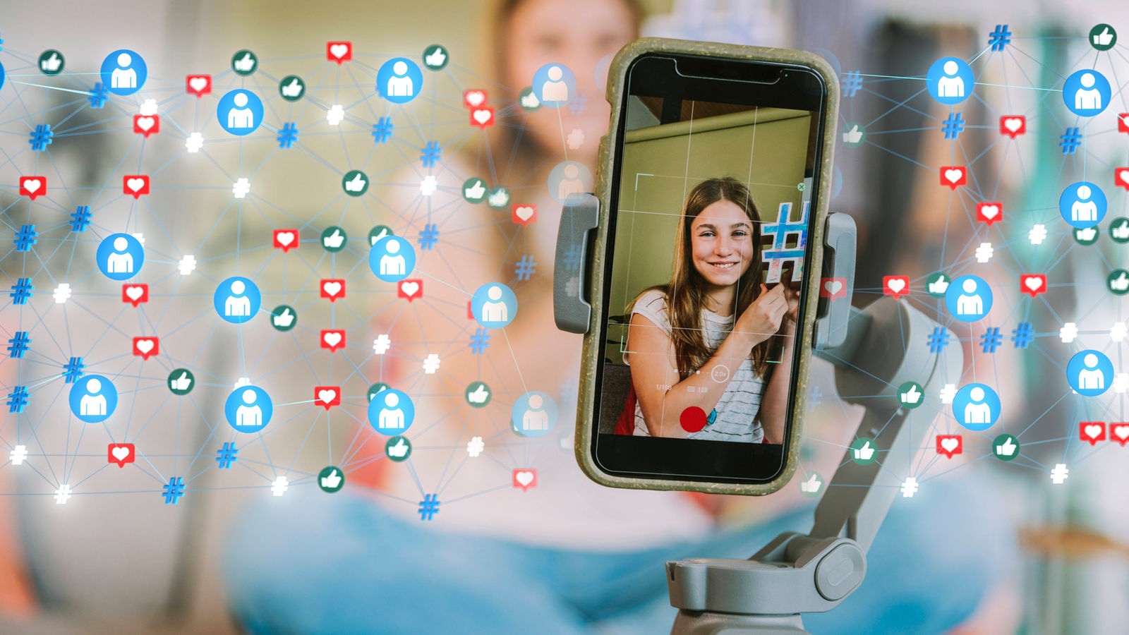 Fotocollage: Smartphone auf Stativ, das eine junge Influencerin zeigt. Daneben zahlreiche Symbole und Emojis
