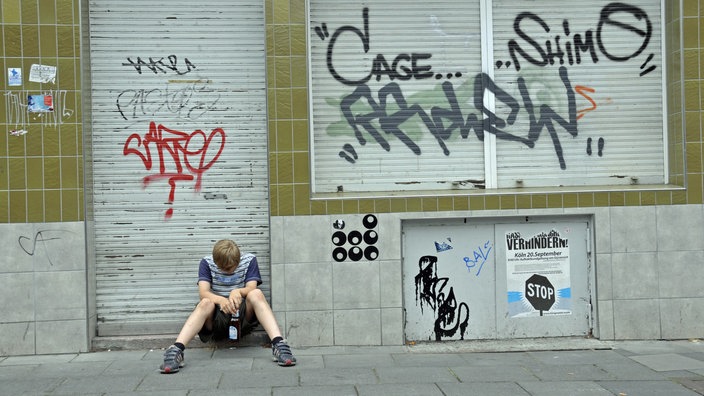 Jugendlicher vor verschlossenem Laden.