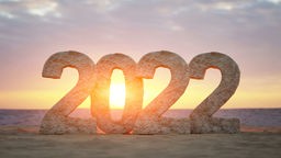 Die Zahl 2022 am Strand vor untergehdner Sonne