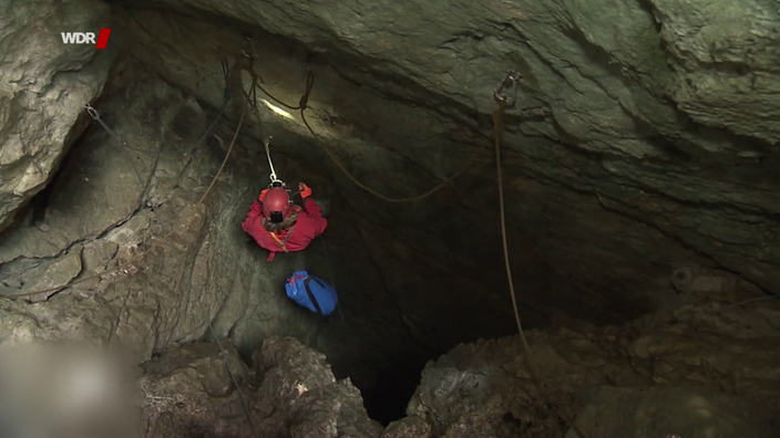 Eine Höhlenretterin der Bergwacht Bayern klettert in eine Höhle