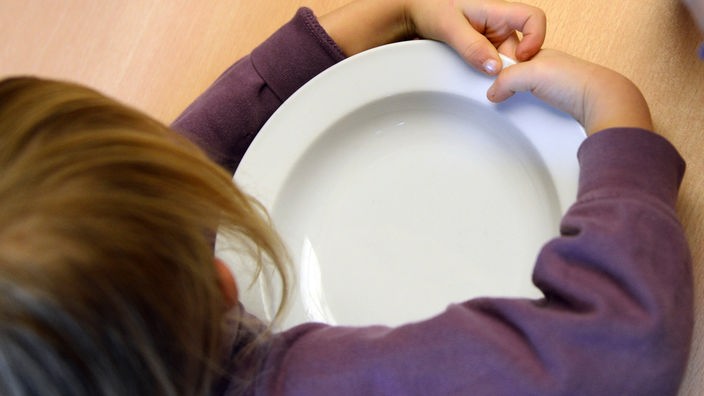 Ein Kind umklammert einen leeren Teller
