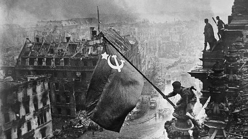 Schwarz-Weiß-Foto: Soldat hisst auf dem Dach des Reichstages die sowjetische Flagge.