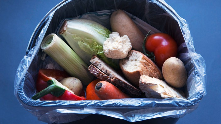 Zwei Packungen Fleisch, eine Dose Margarine und andere Lebensmittel in einer Mülltonne