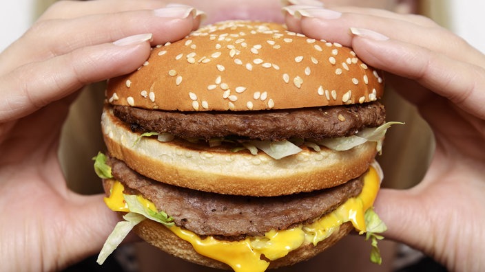 Frau beißt in Hamburger | Bildquelle: imageBROKER / Mauritius images / Simon Belcher Frau beißt in Hamburger