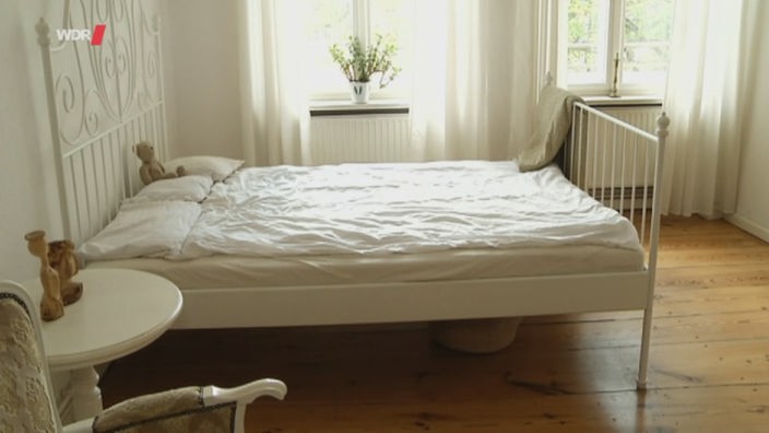 Ein minimalistisch eingerichtetes Schlafzimmer mit einem weißen Bett