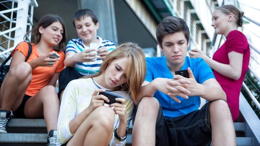 Fünf Jugendliche auf einer Treppe, alle aufs eigene Smartphone starrend