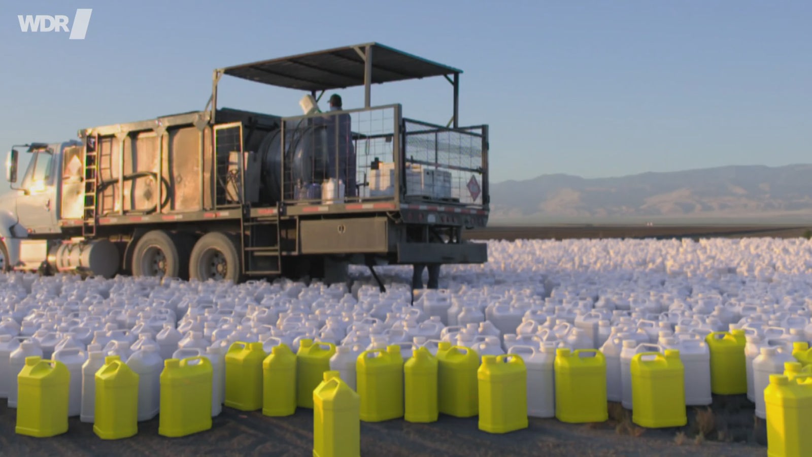 Ein landwirtschaftliches Fahrzeug auf dem Acker, davor zahllose Plastikcontainer