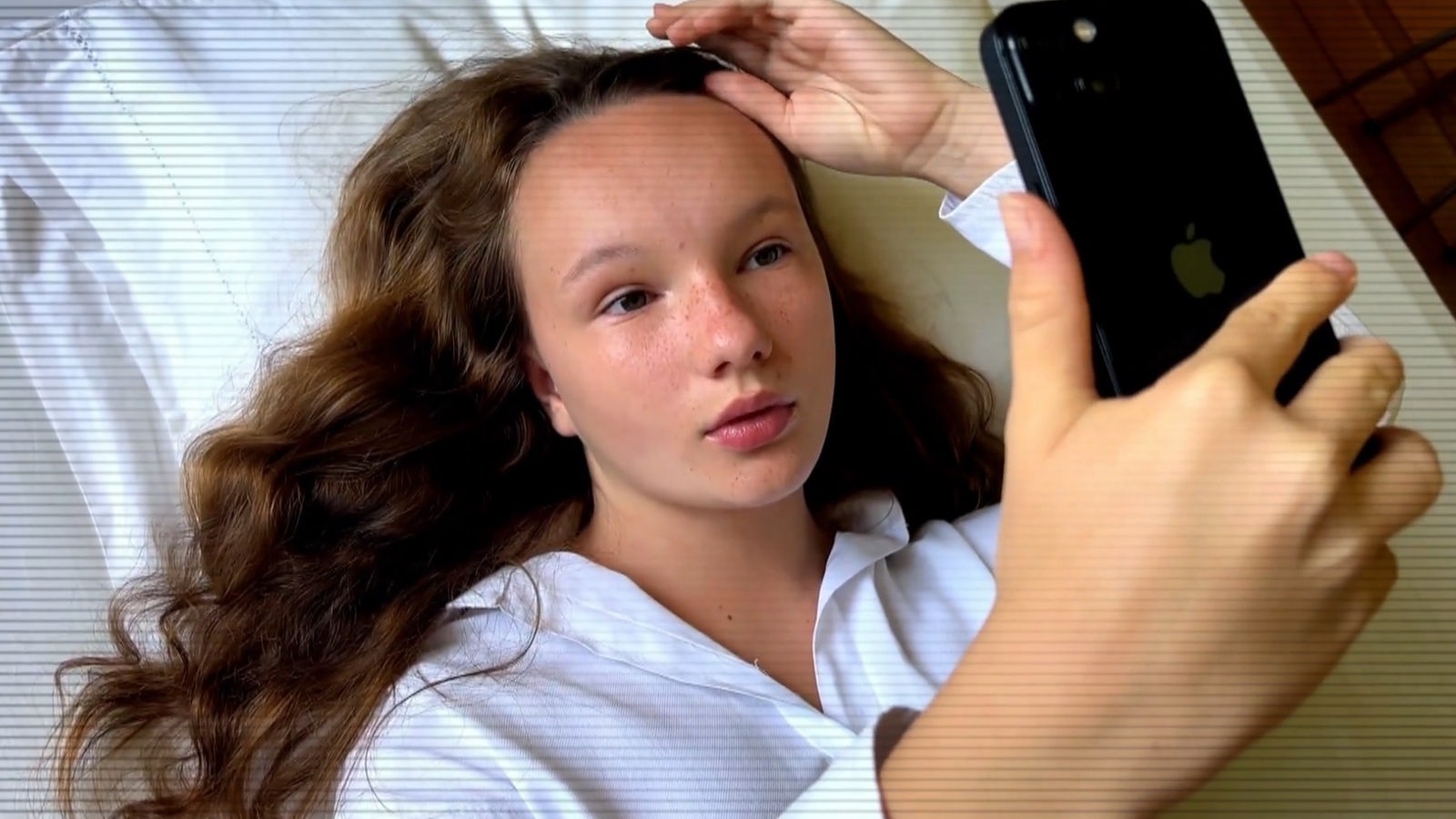 Ein junges Mädchen liegt auf dem Bett und macht ein Selfie