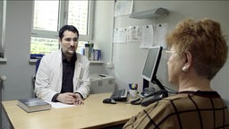 Arzt und Alzheimer-Patientin am Schreibtisch