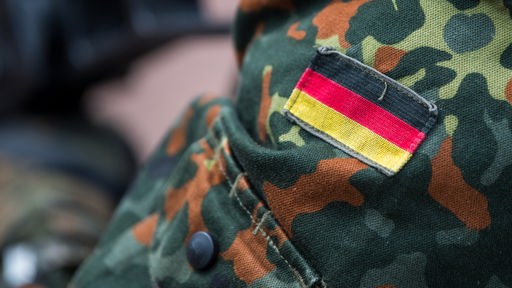 Deutschlandflagge auf dem Oberarm eines Bundeswehrsoldaten im Tarnanzug