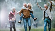Vier Ältere Menschen auf einer Wiese, die lachen und sich freuen