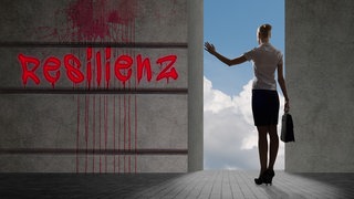 Frau von hinten neben einer Mauer mit der Aufschrift "Resilienz".
