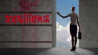 Frau von hinten neben einer Mauer mit der Aufschrift "Resilienz".