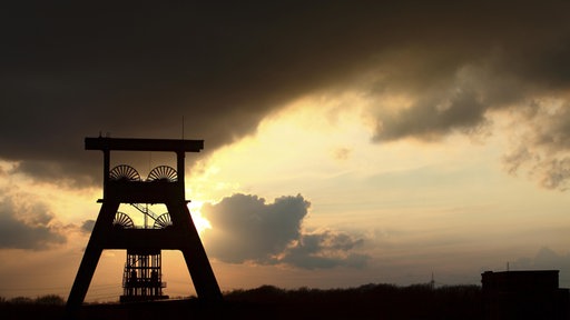 Zechenturm vor untergehender Sonne und dunklem Himmel 