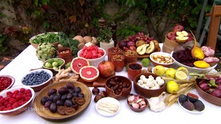 Auf einem Tisch stehen Teller und Schüsseln mit verschiedenen Obst- und Gemüsesorten.
