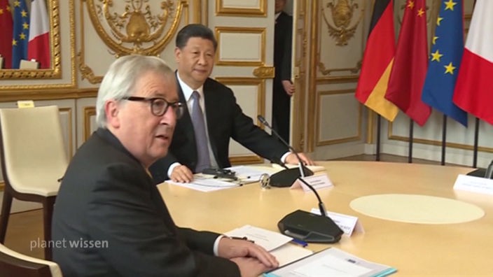 An einem Konferenztisch sitzen der ehemalige Präsident der Europäischen Kommission Jean-Claude Juncker und der chinesische Staats- und Parteichefs Xi Jinping.