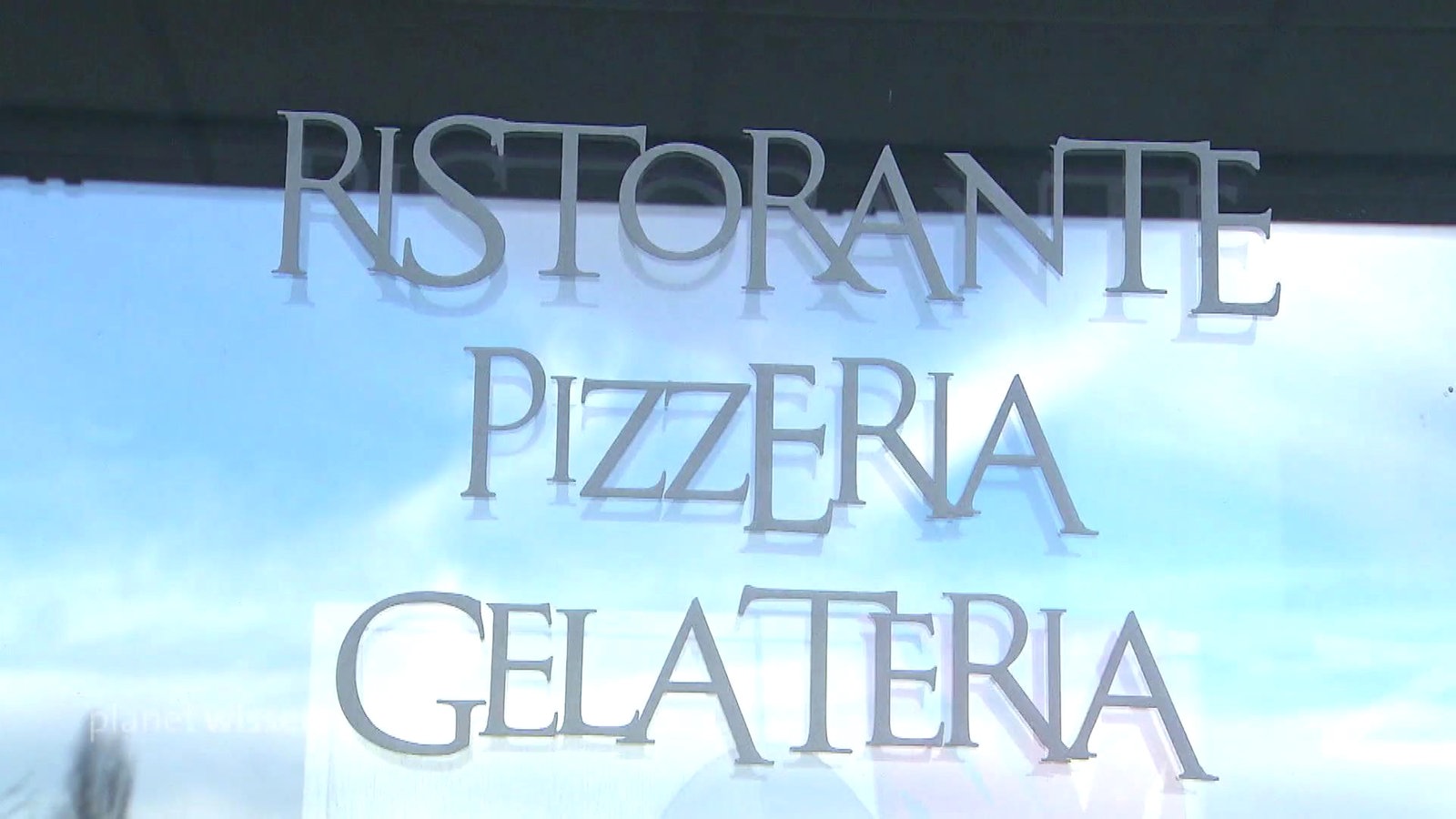 Fensterscheibe auf der der Schriftzug 'Ristorante Pizzeria Gelateria' angebracht ist.