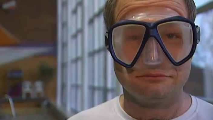 Ein Mann hat eine Taucherbrille auf, die durch die warme Luft beschlagen ist.