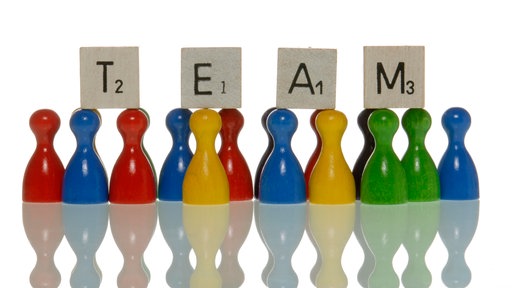 Spielfiguren und Buchstabensteine mit dem Schriftzug "Team".