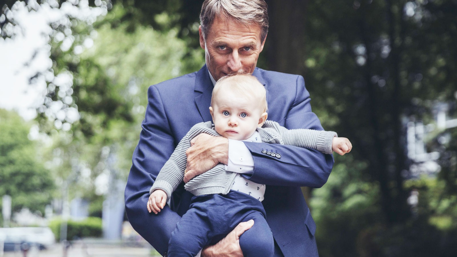 Ein Mann im Anzug hält einen kleinen Jungen auf dem Arm