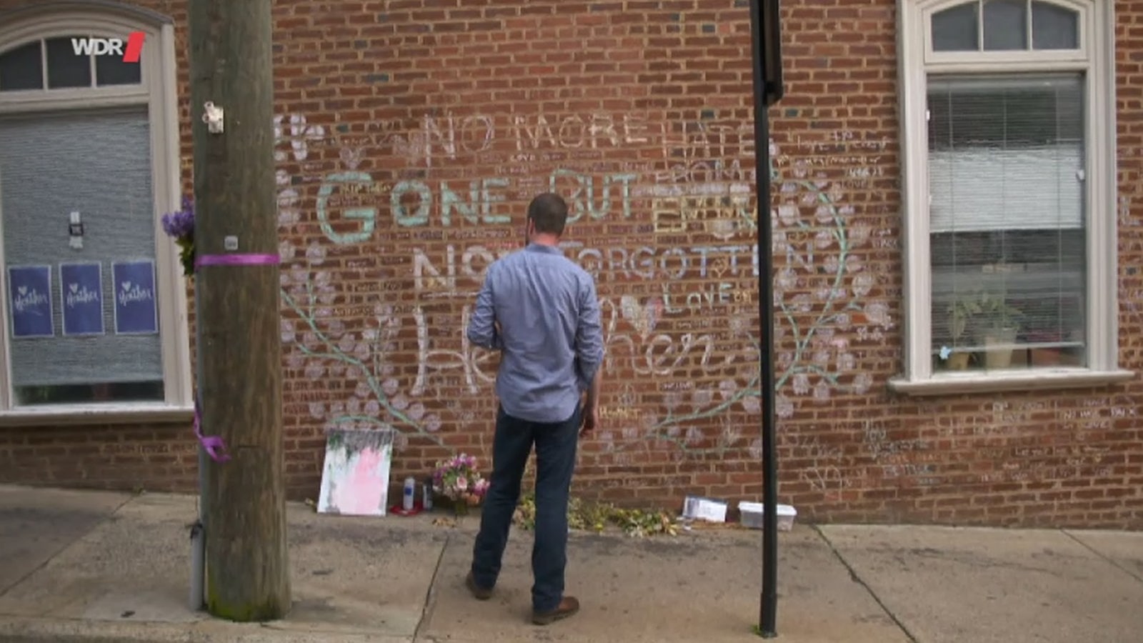 Ein Mann steht vor einer Mauer mit Kreide-Graffiti