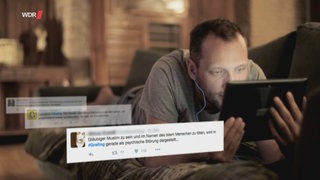 Ein Mann liegt bäuchlings auf dem Bett und schaut auf sein Smartphone