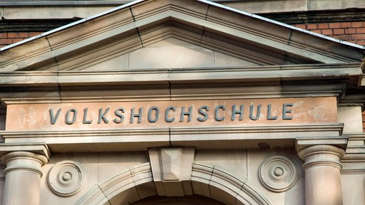 Schriftzug "Volkshochschule" an einem alten Gebäude