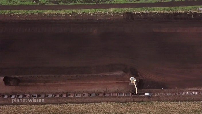 Luftbild auf eine freigelegte Moorfläche auf der ein Bagger steht.